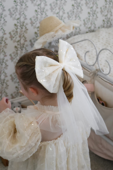 Girl wearing champagne bow veil accessory with puff sleeve flower girl dress Australia, elegant flower girl outfit.