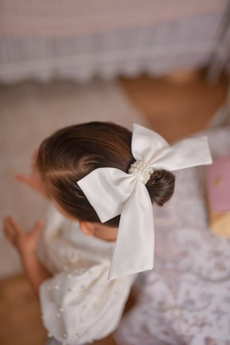 Girl wearing white pearl bow hair accessory with flower girl dress Australia, elegant flower girl outfit.