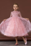 Girl twirling in pink sparkle dress with long sleeves and layered tulle skirt