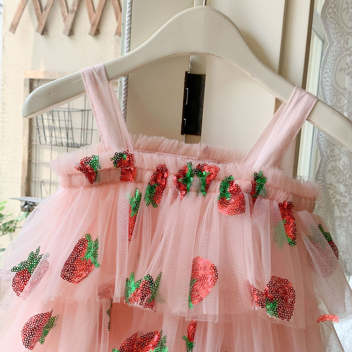 Close-up of pink shoulder straps and ruffled neckline with red and green sequin strawberries on a tulle dress