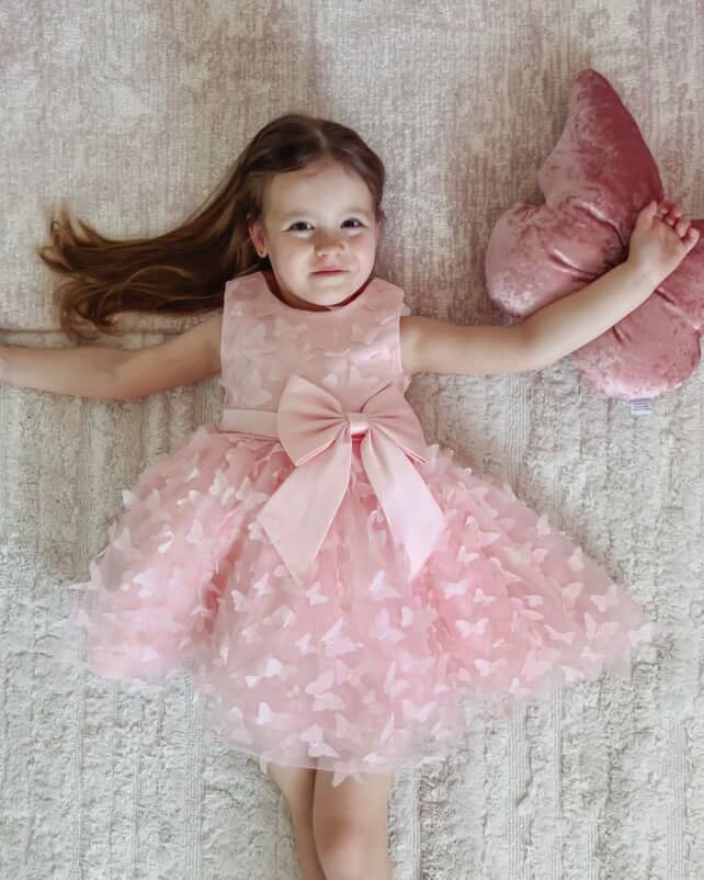 Toddler girl in pink tutu dress with big bow, birthday and party outfit.