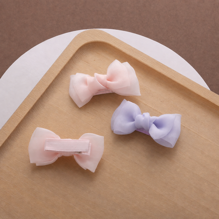 Pastel bow hair clips for girls arranged on a wooden tray