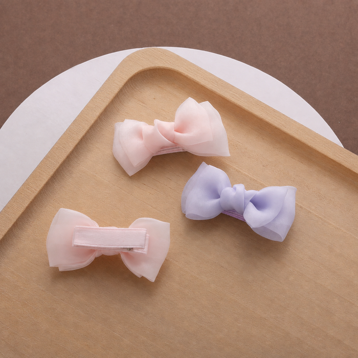 Pastel bow hair clips for girls arranged on a wooden tray