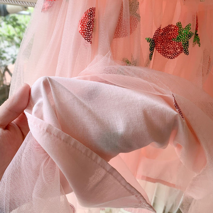 Close-up of the pink lining beneath the strawberry sequin tulle dress, held up to show the inner layer