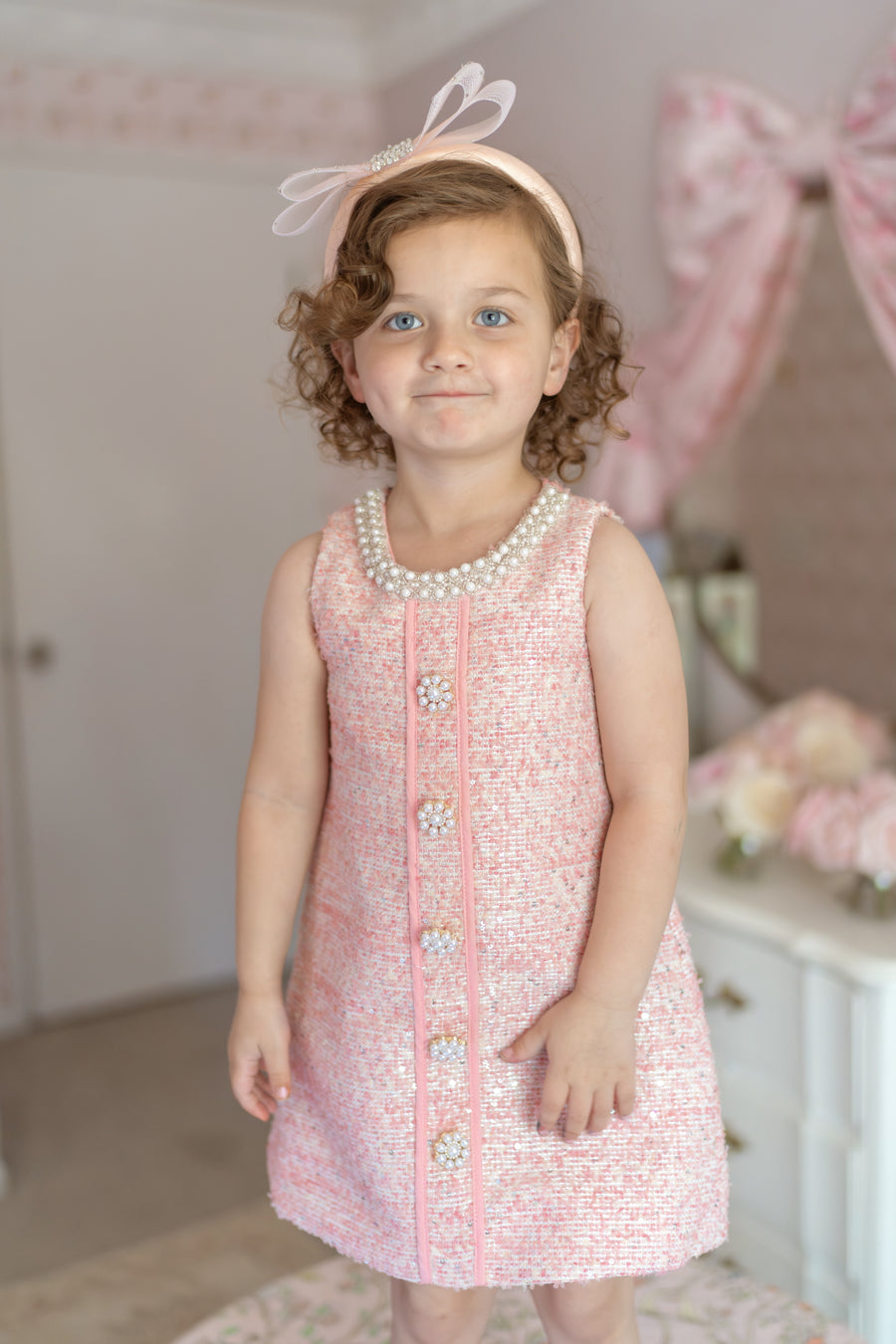 Girl wearing pink bouclé tweed dress with pearl buttons – luxury birthday outfit