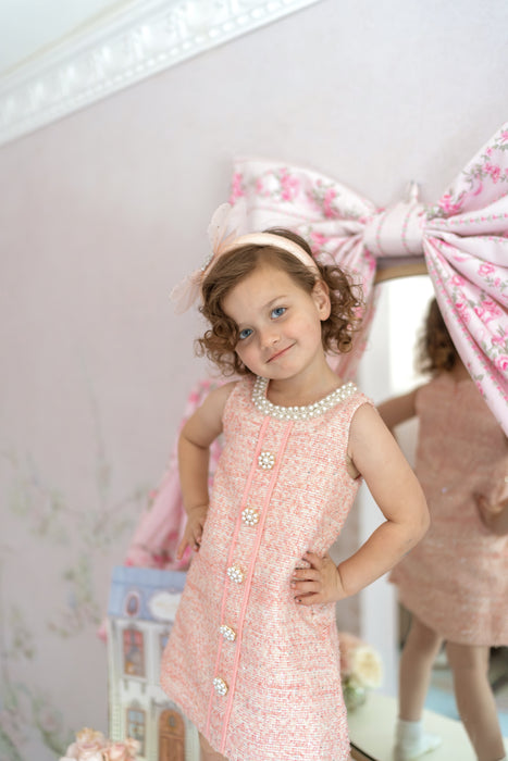 girl in sleeveless pink tweed dress with pearl collar for special occasion